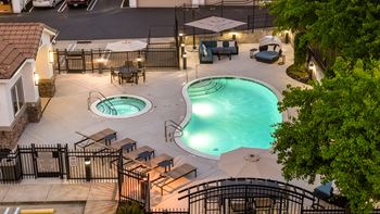 A pool area with two pools and a hot tub surrounded by a fence.